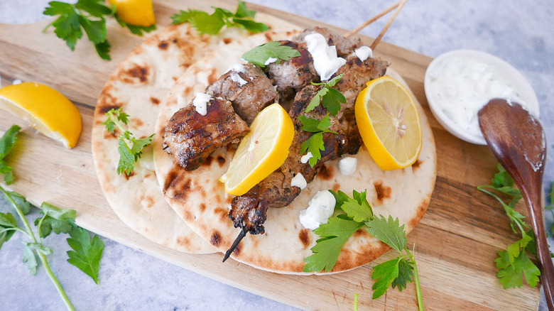 Pork souvlaki skewers on pita with lemon slices and herbs