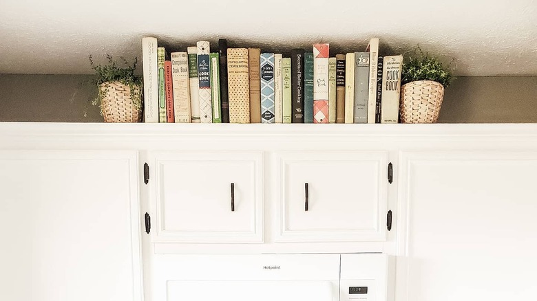 Cookbooks lined up on top of kitchen cabinets.