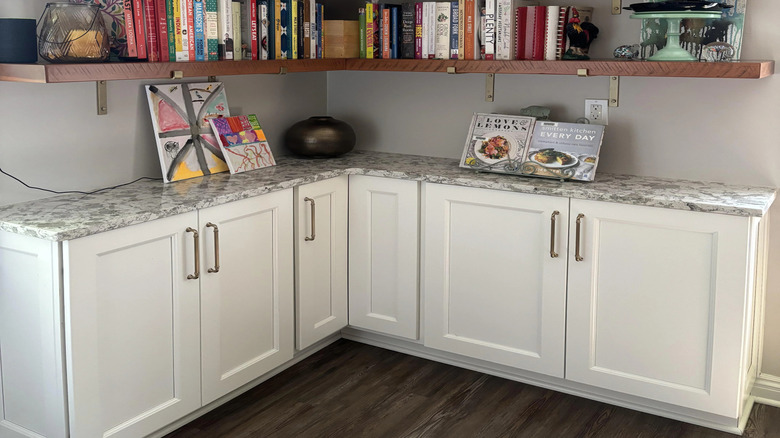 Cookbooks on corner shelves in kitchen.