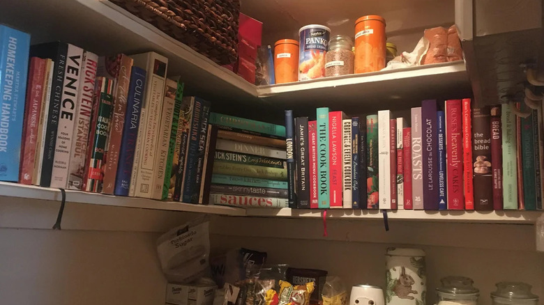Cookbooks stored on pantry shelves.