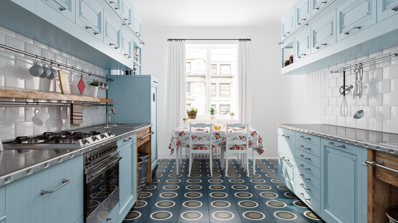 A kitchen with blue cabinets on each side and a dining area at the end