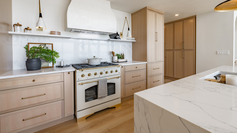 Bright spacious kitchen with a marble island and light wooden cabinets