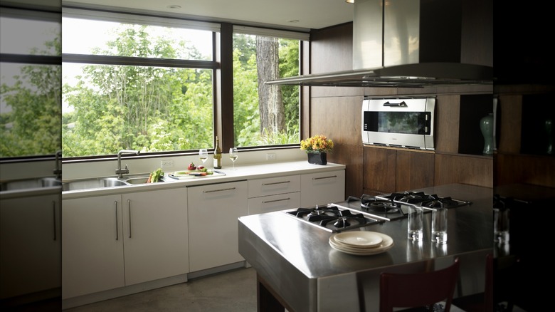 Stainless steel stove and hood, alongside a dark wooden cabinetry and white countertops