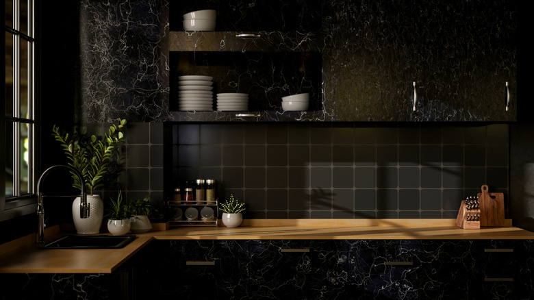 Black kitchen with dark marble cabinets and light wooden countertop