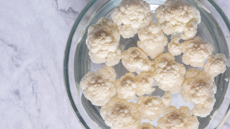 Cauliflower florets soaking in a bowl of water
