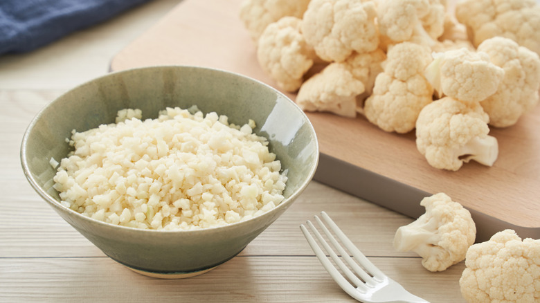 Bowl of cauliflower rice next to fresh cauliflower