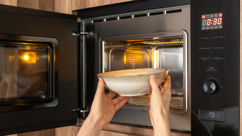 Person putting bowl of cauliflower in microwave