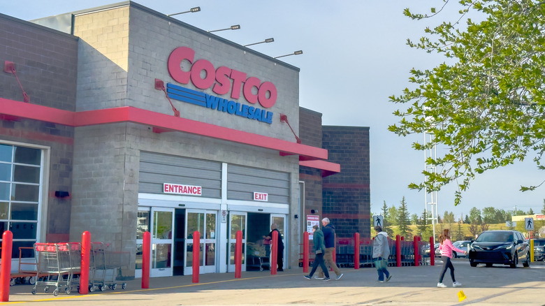 Exterior of a Costco wholesale store with shoppers entering and exiting
