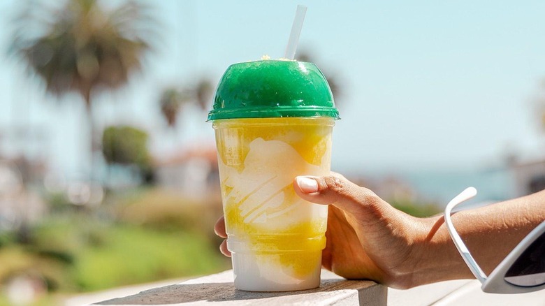 A person holding a Taco Bell cup with a yellow and white swirled frosty drink inside