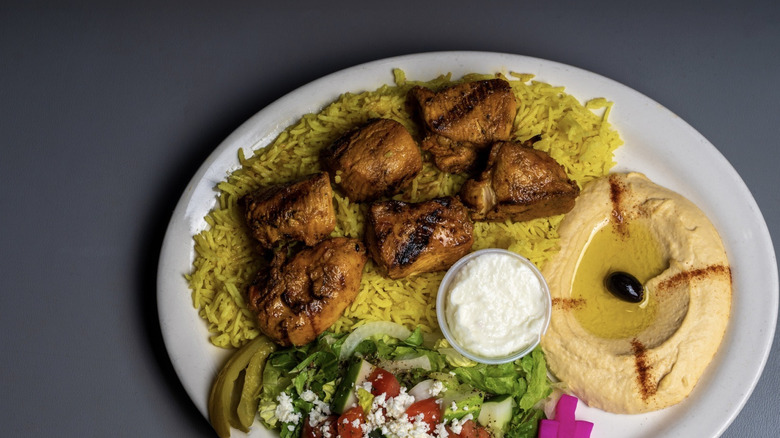 Plate of rice, hummus, salad, and grilled meat at Babylon Restaurant