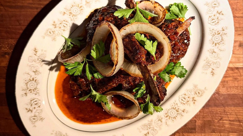 Lamp chops with charred onions on white plate at Mabel Gray