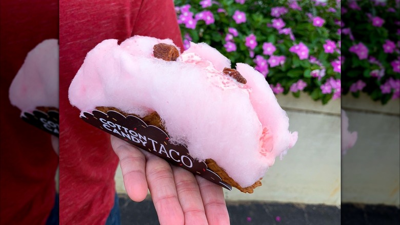 Mirrored image of person holding cotton candy taco on outstretched hand