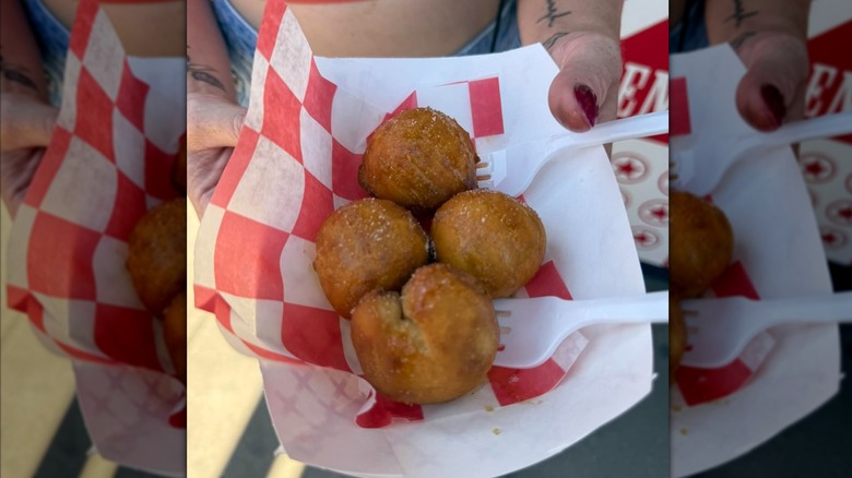 Mirrored image of hands holding dish of fried butter with plastic forks