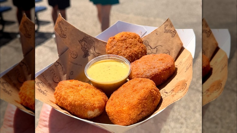 Close up of Eataly takeout dish with deep-fried carbonara bites and sauce, mirrored image