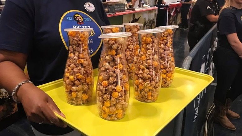 Close up of person holding yellow tray with containers of pinot noir popcorn