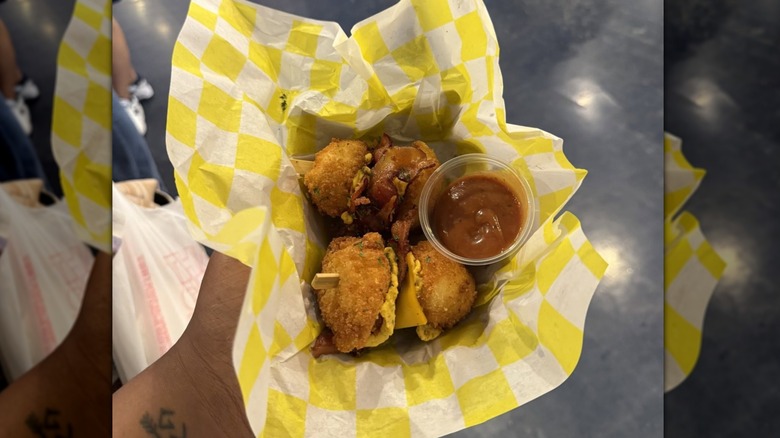Mirrored image of hand holding deviled egg sliders in yellow check packaging