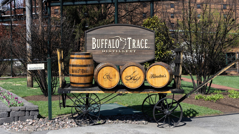 The sign outside of Buffalo Trace distillery above a cart with branded whiskey barrels