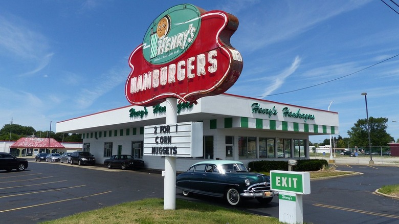 Exterior of Henry's Hamburgers with red sign and vintage car