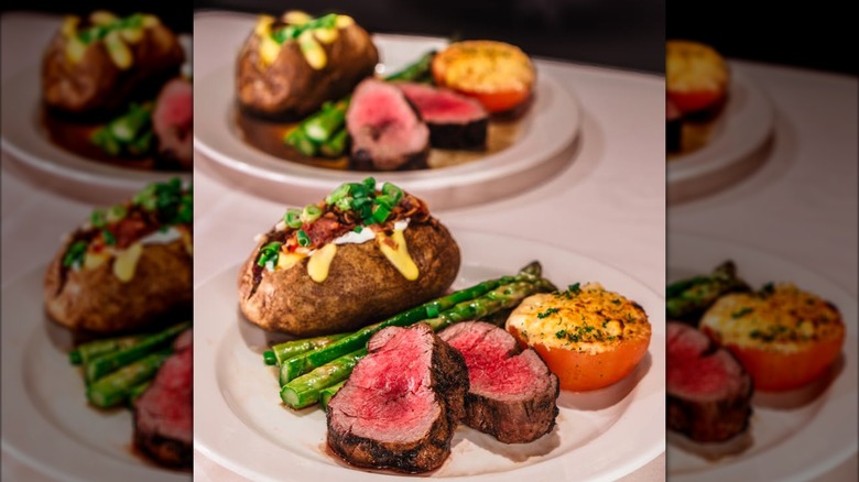 Slices of tenderloin on plates with asparagus and baked potato