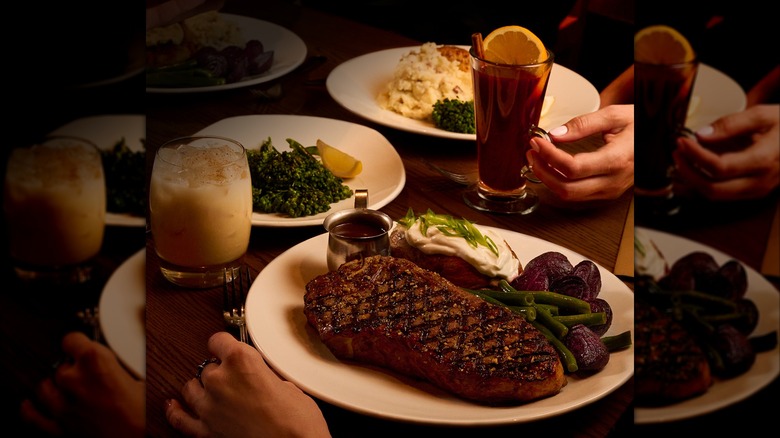 Table set with plated of steaks and sides with cocktails