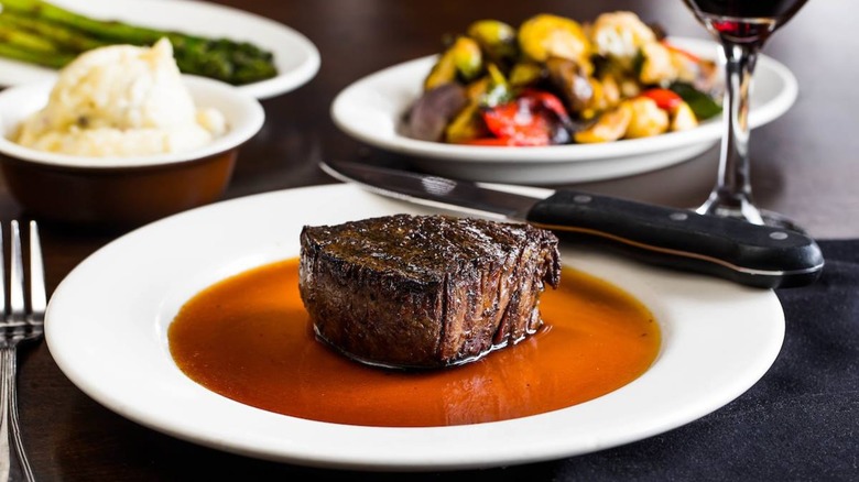 Filet on plate with sides and wine blurred in background