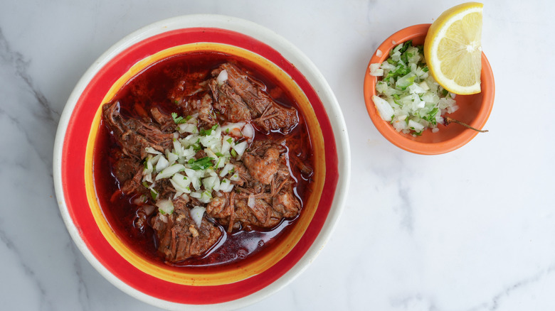 A bowl of Mexican birria with chopped onions and cilantro.