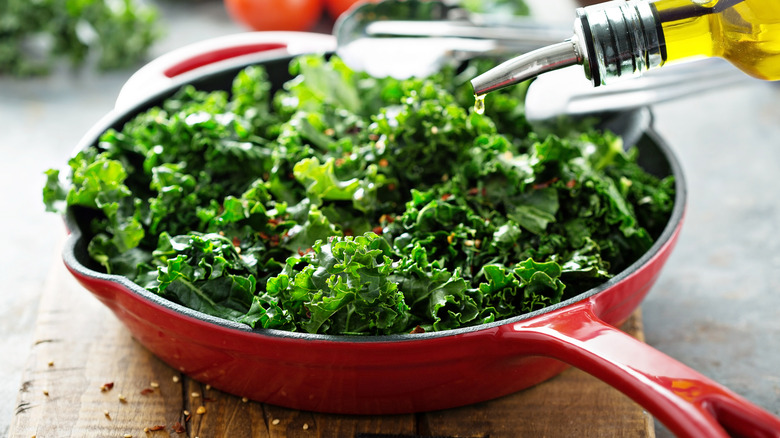 Kale and chili flakes in a red cast iron pan.