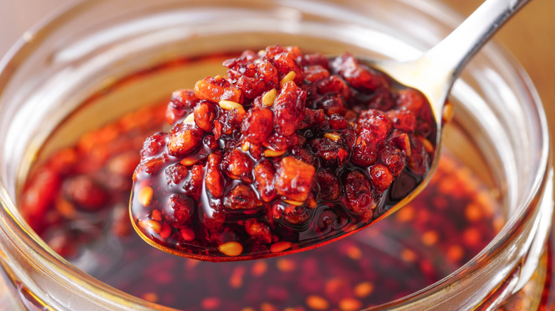 Close-up of a spoon of chili crisp with oil, chiles and garlic.