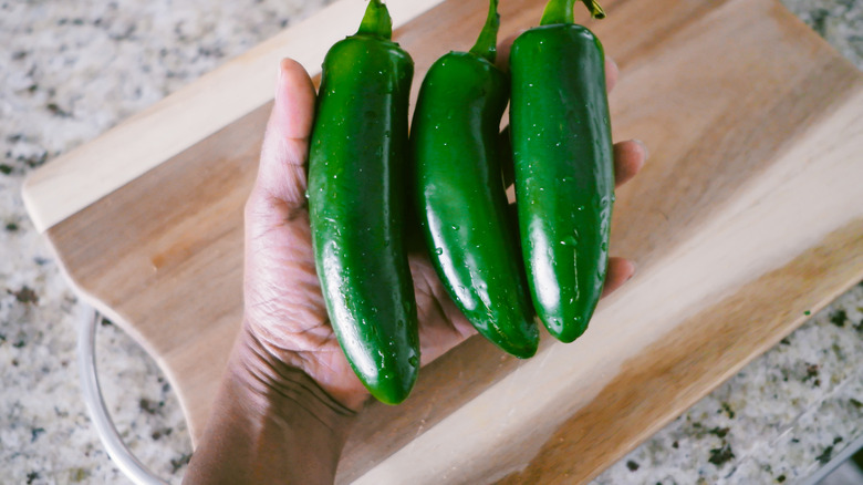Three jalapeño peppers over a cutting board