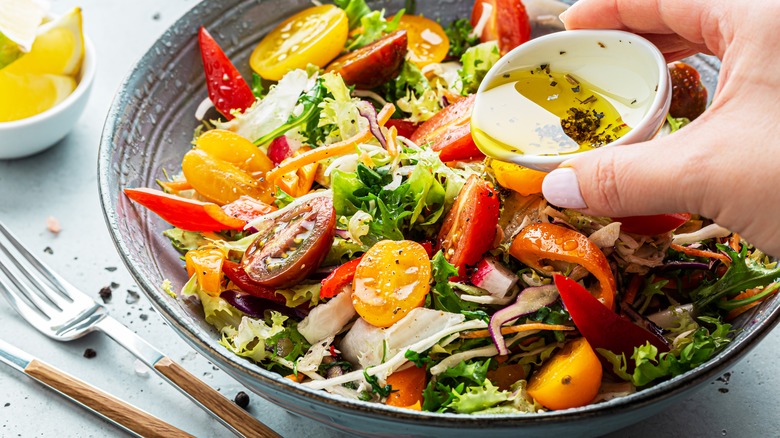 woman pouring dressing over salad
