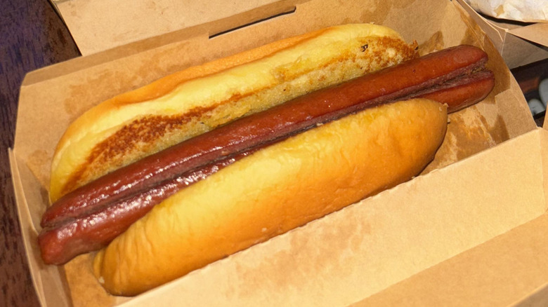 Undressed Shake Shack hot dog in a cardboard box with some crinkle fries visible in the background