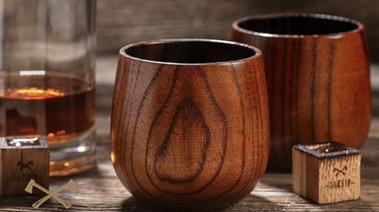 Oaksip's wooden glasses next to wooden blocks and bourbon