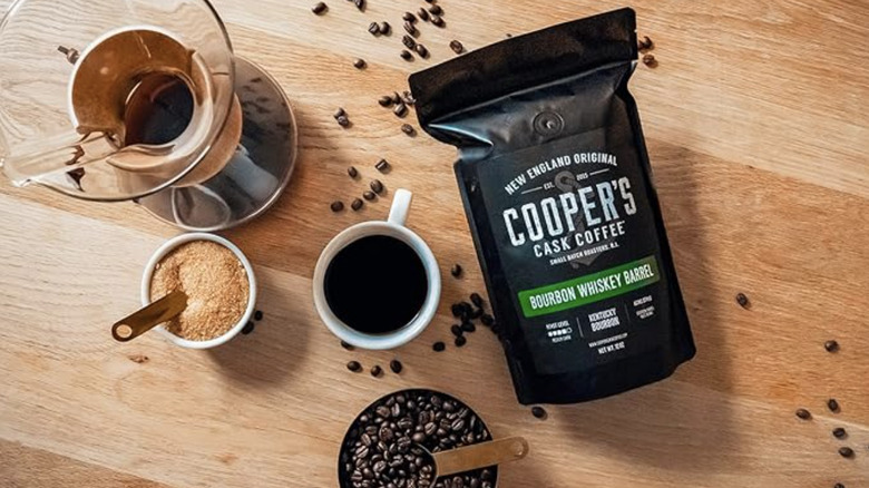 Cooper's Cask Bourbon Whiskey Barrel Coffee package next to beans and glasses