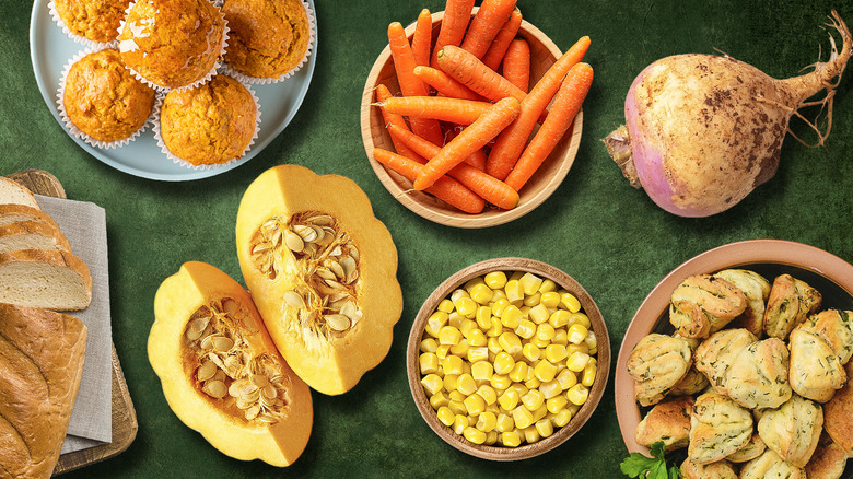 Bowls of different vegetables and baked goods on green background