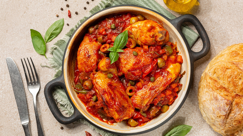 Top view of chicken cacciatore served in a black and white bowl with bread on the side