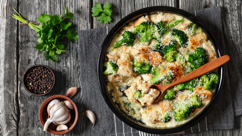 Chicken Divan served in a black baking dish, with garlic and herbs surrounding it