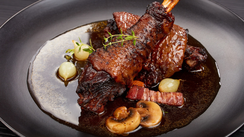 Close up of coq au vin on a black plate