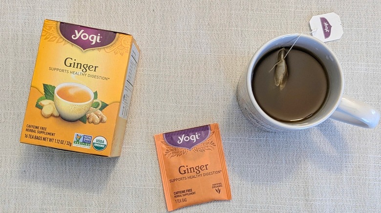 A box of Ginger tea, a tea bag, and a mug on a white tablecloth