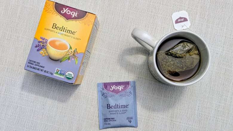 A box of Bedtime tea, a tea bag, and a mug on a white tablecloth