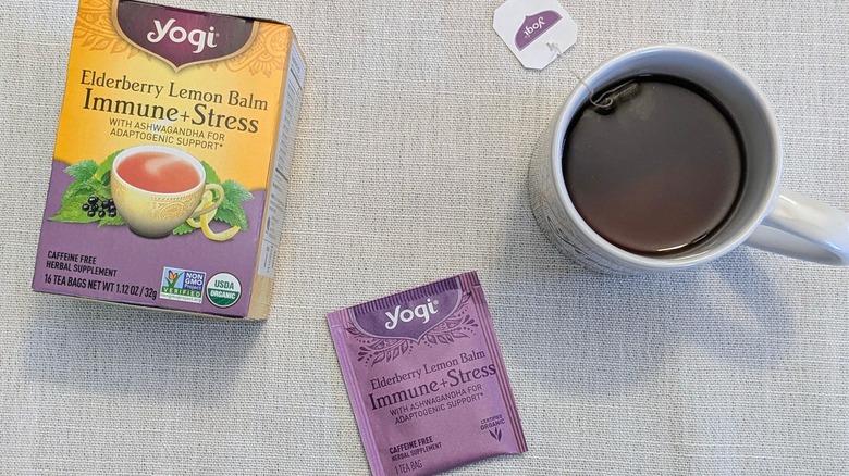 A box of Elderberry Lemon Balm Immune + Stress tea, a tea bag, and a mug on a white tablecloth