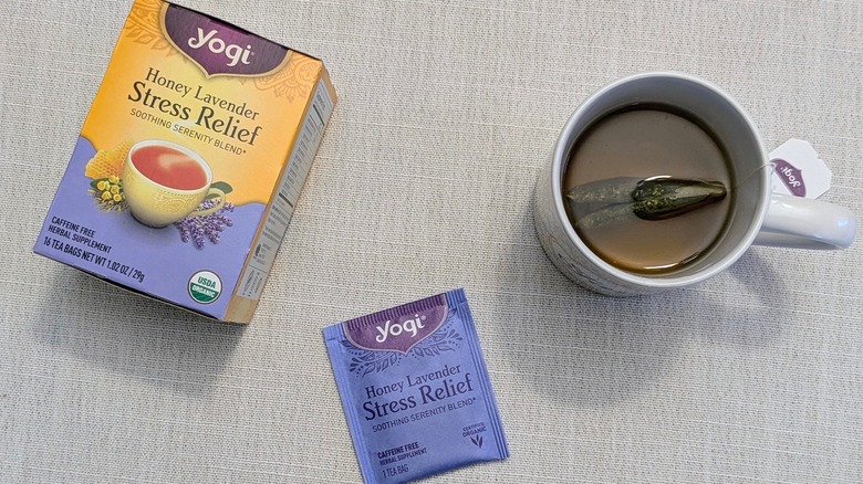 A box of Honey Lavender Stress Relief tea, a tea bag, and a mug on a white tablecloth