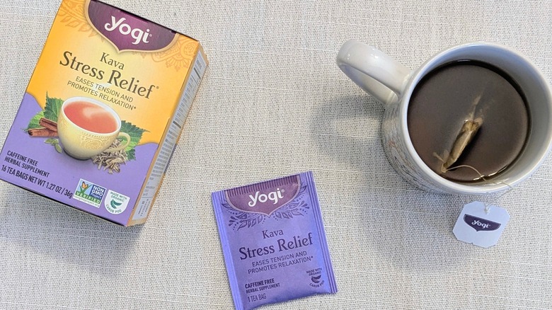 A box of Kava Stress Relief tea, a tea bag, and a mug on a white tablecloth