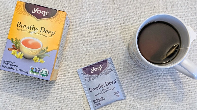 A box of Breath Deep tea, a tea bag, and a mug on a white tablecloth