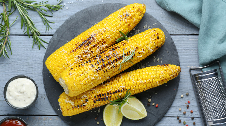 Grilled corn on grey platter with lime wedges