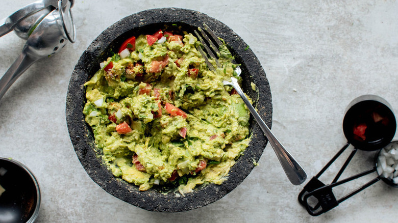 Homemade guacamole in grey bowl with fork