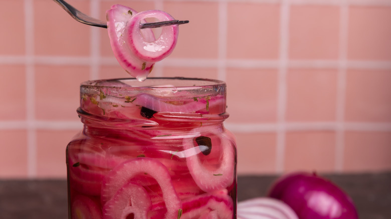 Forkful of pink pickled onion held over jar