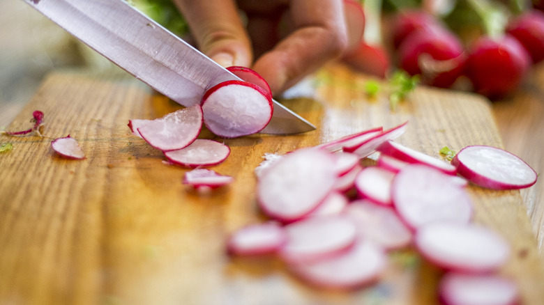 Slicing radishes on wooden cutting board
