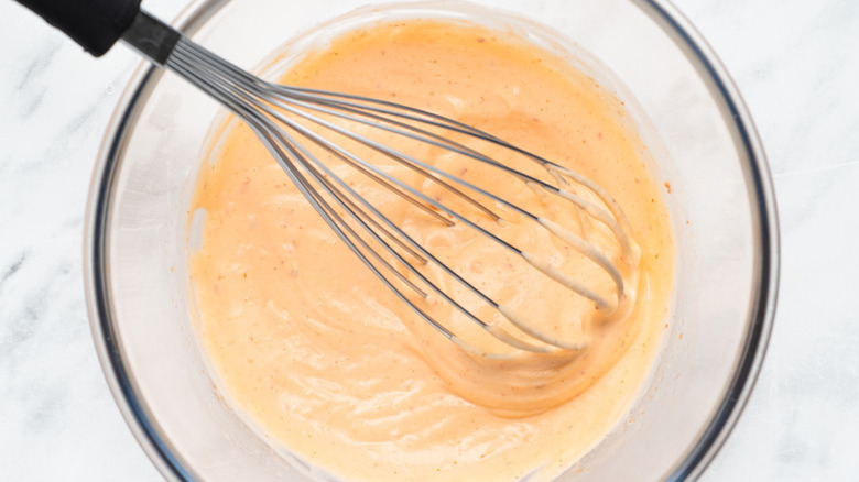 Whisking sriracha mayo in glass mixing bowl