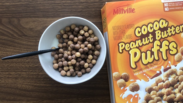 Bowlful of Millville Cocoa Peanut Butter Puffs with milk and spoon.