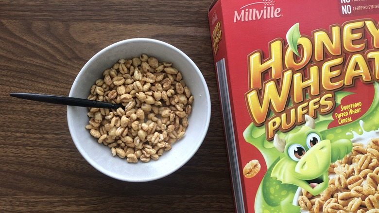 Bowlful of Millville honey wheat puffs with milk and spoon.